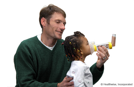 Placing the mask spacer over the child's mouth and nose