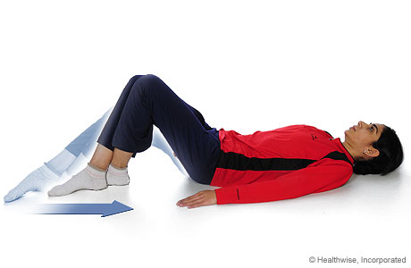 A woman doing the knee-flexion-with-heel-slide exercise